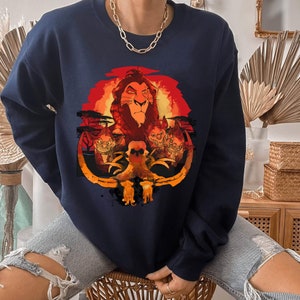 May include: A navy blue sweatshirt with a graphic print of Simba, the lion from The Lion King, with a sunset background. The graphic also includes hyenas and a skull.