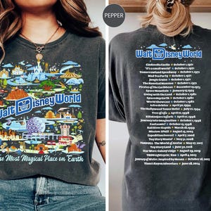 Pu&ograve; includere: Una maglietta grigia scura con un'illustrazione colorata di Walt Disney World, che include attrazioni e monumenti iconici. Il testo "Walt Disney World" e "The Most Magical Place on Earth" sono stampati sulla maglietta. Il retro della maglietta presenta un elenco delle attrazioni di Walt Disney World e delle loro date di apertura.