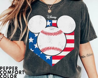 May include: A dark grey t-shirt with a baseball graphic featuring Mickey Mouse ears and a baseball with red, white, and blue stars and stripes. The text "Disney" is printed above the graphic.
