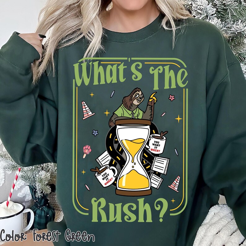 Puede incluir: Sudadera verde bosque con un gr&aacute;fico que presenta un perezoso, un reloj de arena y el texto "What's The Rush?". El dise&ntilde;o incluye tazas de caf&eacute; y conos de tr&aacute;fico. El texto "You want it when?" est&aacute; en las tazas de caf&eacute;.