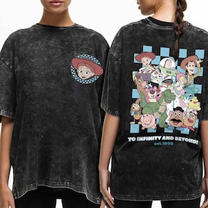 May include: Black t-shirt with a distressed look featuring a Toy Story character print on the front and back. The front features a close-up of Jessie, while the back features a group of Toy Story characters including Woody, Buzz Lightyear, and Rex. The back also includes the text "To Infinity and Beyond! est.1995".
