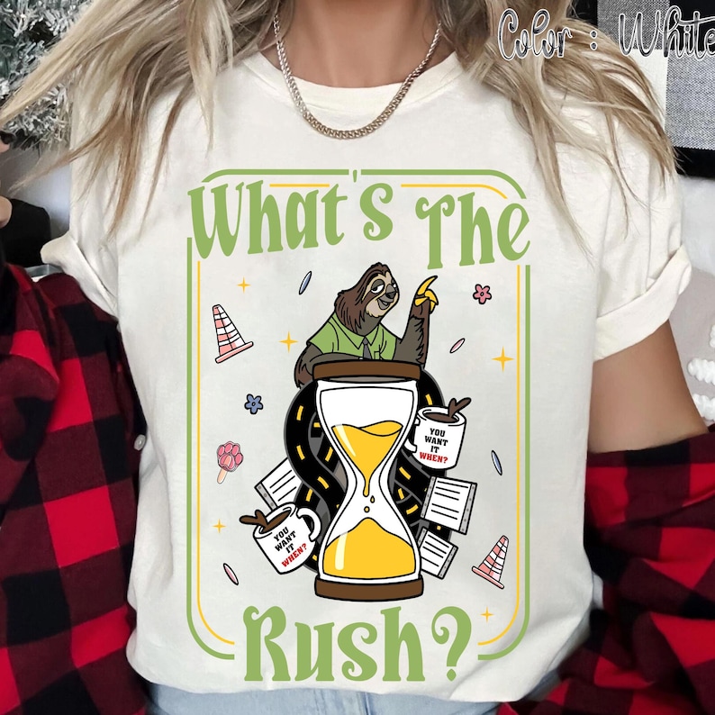 Puede incluir: Camiseta blanca con un gr&aacute;fico humor&iacute;stico que presenta un perezoso, un reloj de arena y el texto "What's The Rush?". El dise&ntilde;o incluye tazas de caf&eacute; y elementos de carretera, creando un tema l&uacute;dico. La camiseta es de material suave.