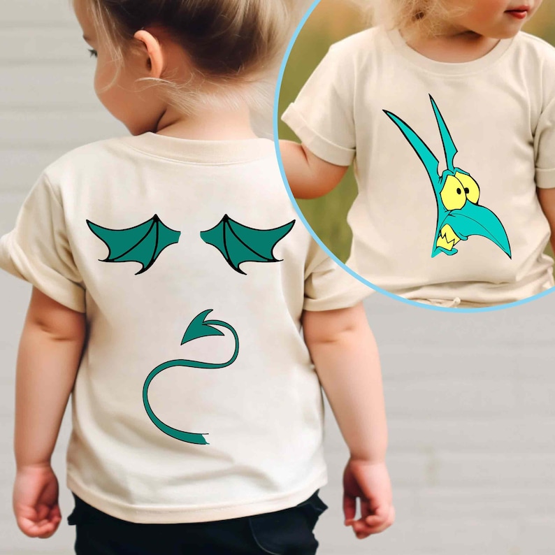 Pode incluir: Camiseta bege clara para crian&ccedil;as pequenas com um desenho de drag&atilde;o de desenho animado turquesa. A frente mostra uma cabe&ccedil;a de drag&atilde;o turquesa com olhos amarelos. A parte de tr&aacute;s tem asas e uma cauda turquesas, criando um efeito de fantasia de drag&atilde;o.