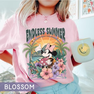 May include: Pink t-shirt with a graphic featuring Minnie Mouse in a tropical setting with palm trees, flowers, and the words "ENDLESS SUMMER." The shirt also has the word "BLOSSOM" at the bottom.