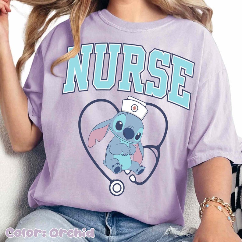 May include: Orchid-colored t-shirt with the word "NURSE" in light blue block letters. A cartoon character wearing a nurse's cap is inside a stethoscope-shaped heart. The shirt's color is labeled "Color: Orchid".