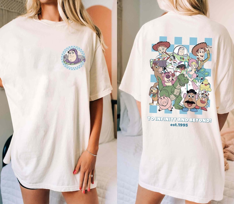 May include: White oversized t-shirt with a blue and white checkered pattern on the back. The back features a graphic of characters from the Toy Story movie franchise. The text "TO INFINITY AND BEYOND! est. 1995" is printed below the graphic. The front of the shirt features a small graphic of the character Buzz Lightyear.