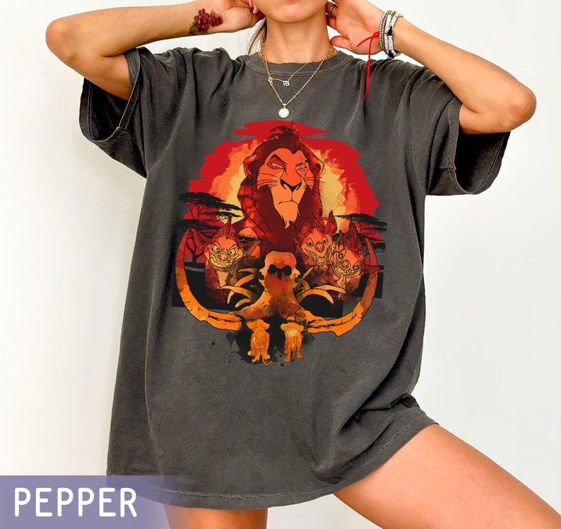 May include: A dark grey t-shirt with a graphic print of Simba, the lion from The Lion King, with a sunset background. The graphic also includes hyenas.