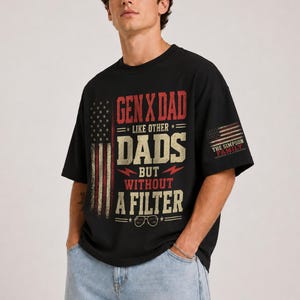 Pode incluir: Camiseta preta com o texto "GEN X DAD LIKE OTHER DADS BUT WITHOUT A FILTER" em vermelho e branco. O design inclui uma bandeira americana e o texto "THE SIMPSON FAMILY" na manga.