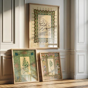 May include: Three framed Islamic calligraphy art pieces. The largest features ornate green and gold borders with Arabic script. Two smaller pieces lean against the wall, one with green and gold, the other with floral borders. All are displayed on a wooden floor.