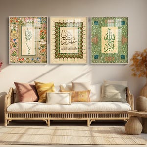 May include: Three framed Islamic calligraphy art pieces. The artwork features ornate floral and geometric patterns in shades of green, gold, and beige. The calligraphy is in black ink. The frames are white.