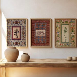 May include: Three framed art prints with Arabic calligraphy and ornate patterns. The prints are in wooden frames and feature intricate designs in shades of blue, red, and floral motifs. The artwork is displayed on a wooden table with two ceramic vases and three small cups.