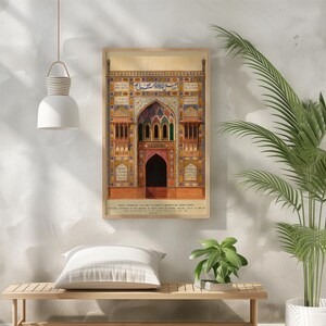 May include: A vintage illustration of a colorful, ornate building with intricate details and Arabic script. The building has a large arched entrance and multiple windows. The illustration is framed in a wooden frame.