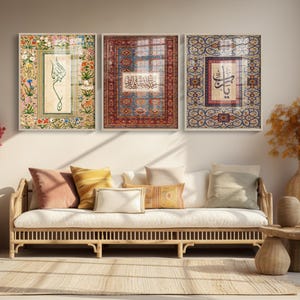 May include: Three framed art pieces with ornate designs and calligraphy hang above a white sofa with pillows. The art features floral and geometric patterns in shades of red, blue, and beige. A wooden side table and vase are in the foreground.