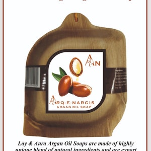 Könnte beinhalten: Eine braune, hölzerne Seifenschale mit einem Etikett, auf dem "Arq-E-Nargis Argan Oil Soap" steht. Das Etikett zeigt eine Zeichnung eines Frauen Gesichts und Arganöl-Nüsse.
