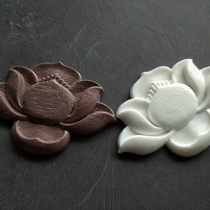 May include: Two decorative lotus flower sculptures, one brown and one white, with intricate details.