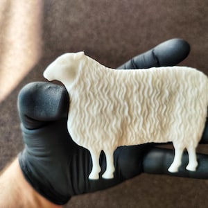 May include: A white 3D printed sheep figurine with a wavy textured surface. The sheep is standing on its four legs and has a small head with a pointed nose.