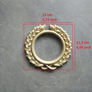 Può includere: Corona in metallo dorato con un'apertura circolare al centro. La corona ha un diametro di 12 cm e un'altezza di 11,3 cm.