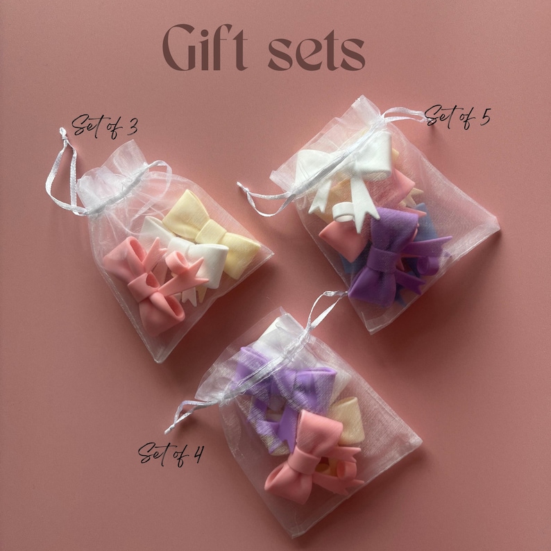 Pu&ograve; includere: Tre sacchetti di organza pieni di set di fiocchi di stoffa colorati. I sacchetti sono etichettati "Set of 3", "Set of 4" e "Set of 5".