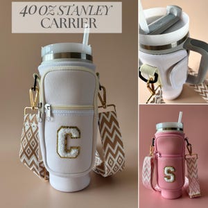 Puede incluir: Un portador Stanley de 1,18 litros de color crema con cremallera dorada, correa estampada y una letra "C" blanca. El portador tiene un interior blanco y una pajita. El texto "40 OZ STANLEY CARRIER" está en la parte superior.