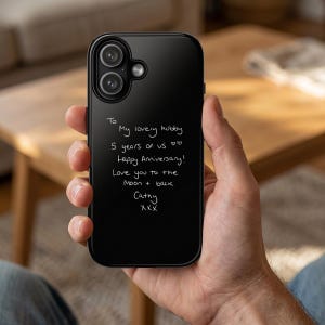 May include: A black phone case with a handwritten message. The message reads "To My lovely hubby, 5 years of us, Happy Anniversary! Love you to the Moon + back, Cathy, XXX". The phone case has a dual-lens camera.