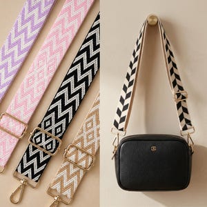 May include: A black crossbody bag with a gold emblem and a patterned strap. The straps are available in various colours, including lavender, pink, black, and tan, with gold-tone hardware.