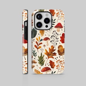 Puede incluir: Una funda de teléfono con un patrón repetido de hojas de otoño, setas y bayas en tonos rojos, naranjas, verdes y marrones sobre un fondo crema. La funda se muestra de frente y de lado.