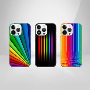 Könnte beinhalten: Drei Handyhüllen mit farbenfrohen Designs. Eine Hülle hat ein Regenbogenfächer-Design, eine andere vertikale Regenbogenstreifen auf schwarzem Hintergrund, und die dritte hat Regenbogenstreifen, die sich im Wasser spiegeln.