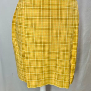 May include: A yellow plaid skirt with a brown belt. The skirt has a pleated design and a straight hemline.