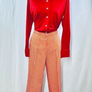 May include: A red collared shirt with long sleeves and white buttons, paired with orange and white striped pants.