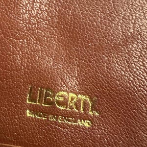 ヴィンテージ リバティ ブラウン レザーにリバティ シルク プリント生地を使用。メイン コンパートメント 1 つと紙幣用コンポーネント 4 つ。希少価値のある美しい品です。