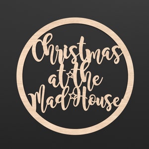 A wooden Circle Hoop with the wording Christmas at the Madhouse cut out of the centre of it.