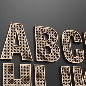 Wooden A B C letters with each letter having a rattan pattern cut out of the middle of it.