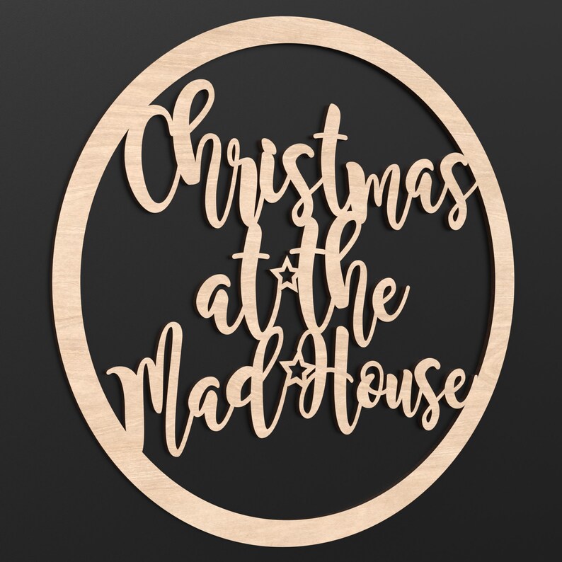 A wooden Circle Hoop with the wording Christmas at the Madhouse cut out of the centre of it.