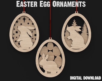 May include: Three wooden Easter egg ornaments with a bunny rabbit design. Each ornament has a different design: one with stars, one with a forest scene, and one with a pattern of eggs.