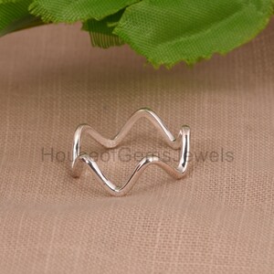 Peut inclure: Une bague en argent avec un design ondulé. La bague est faite d'une seule pièce de métal qui est pliée en forme d'onde.
