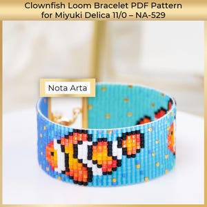 May include: A turquoise and blue beaded loom bracelet with a clownfish pattern. The bracelet incorporates orange, white, and black beads. The image includes the text "Nota Arta". The bracelet is crafted with Miyuki Delica 11/0 beads.
