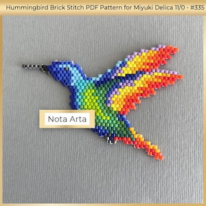 Pode incluir: Um beija-flor de contas coloridas com um padrão de arco-íris. O beija-flor é feito com contas pequenas e é um padrão de ponto de tijolo. A imagem inclui o texto "Nota Arta".