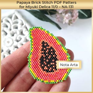 Puede incluir: Un motivo de papaya hecho con cuentas en punto ladrillo usando Miyuki Delica 11/0. El diseño presenta un interior de fruta rojo anaranjado vibrante, un grupo central de semillas negras y un borde exterior amarillo y verde. El texto dice Papaya Brick Stitch PDF Patters for Miyuki Delica 11/0 – NA-131 y Nota Arta.