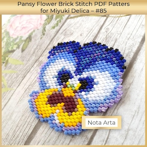 Könnte beinhalten: Nahaufnahme einer Perlen-Stiefmütterchen-Blume in den Farben Blau, Weiß, Gelb und Lila. Die Blume ist mit Miyuki Delica-Perlen gefertigt und mit der Ziegel-Stich-Technik gestickt. Das Bild enthält den Text "Nota Arta".