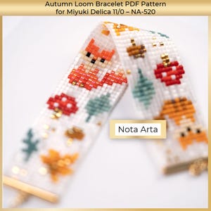 Puede incluir: Pulsera de cuentas blanca con dise&ntilde;os de tem&aacute;tica oto&ntilde;al, incluyendo un zorro, setas y hojas. La pulsera est&aacute; hecha con peque&ntilde;as cuentas y presenta detalles dorados. El texto "Nota Arta" es visible.