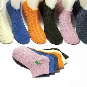 Each of the six pairs of colorful thermal bamboo socks has one sock on a foot and one on the floor.