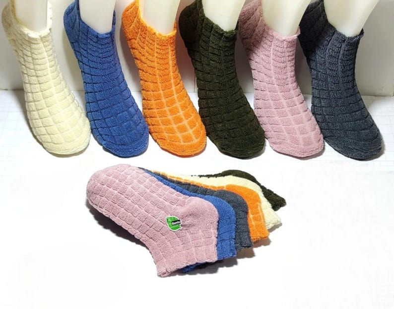 Each of the six pairs of colorful thermal bamboo socks has one sock on a foot and one on the floor.