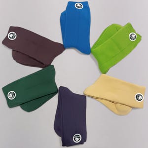 Six pairs of colorful cotton socks displayed in a circular arrangement on a light gray background. Each pair features a small cotton logo, emphasizing comfort and style. Perfect for casual and everyday wear.