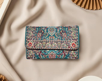 May include: A teal wallet with a detailed, colorful floral pattern. The wallet has a fold-over flap and appears to be made of a woven fabric. The design incorporates red, white, and purple accents, creating a vintage aesthetic.
