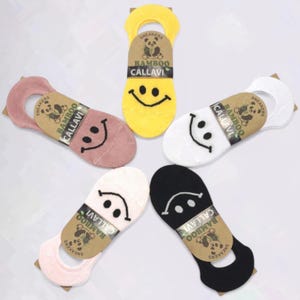 Assorted colorful bamboo no show socks featuring smiley face designs arranged in a star pattern on a white  background.