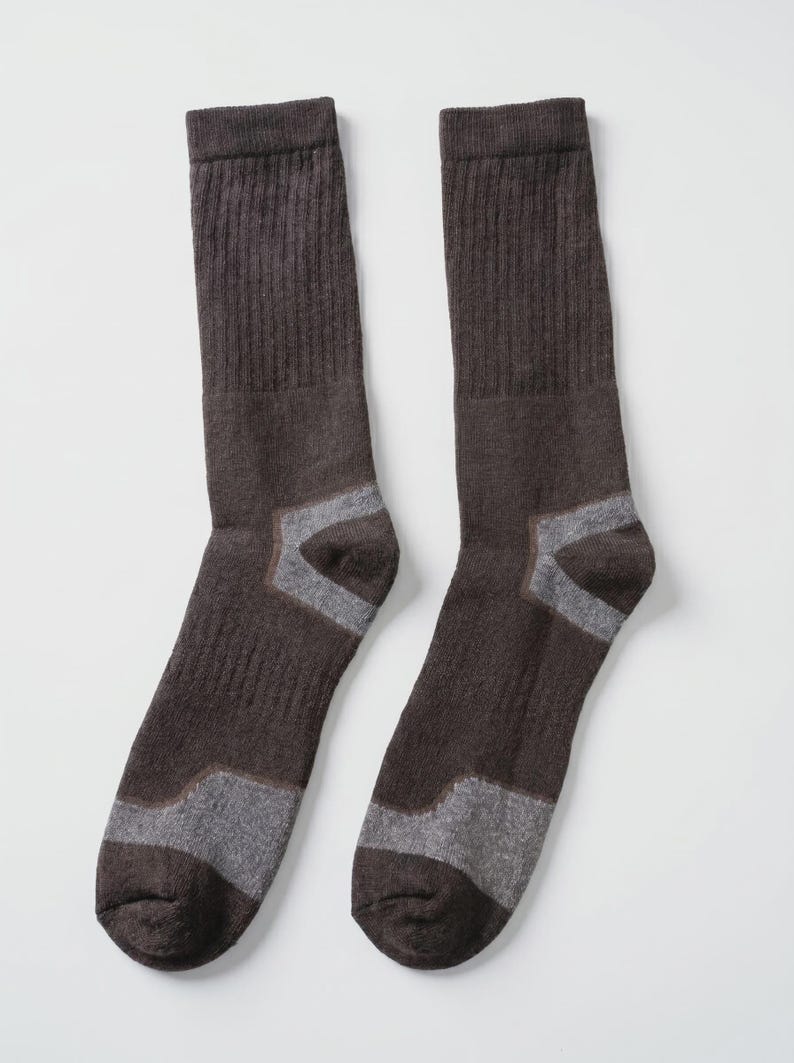 May include: A pair of dark brown crew socks featuring a ribbed texture on the upper leg section and contrasting light gray panels at the heel and toe areas. The socks are constructed with a knit fabric and have a standard mid-calf length design.