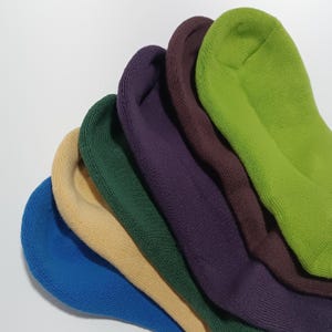 Six pairs of colorful socks displayed overlapping each other in a fan shape focused on the fluffy texture of the ends on a light gray background.