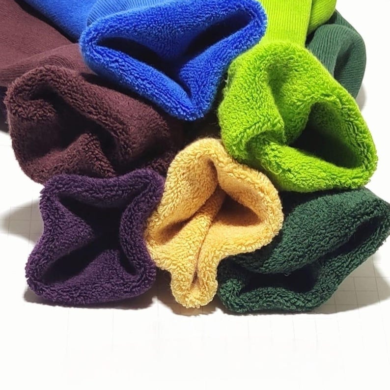 Six pairs of rolled up socks in various color are displayed on a white background. Their colors are: Burgundy, Blue, Green, Light green, Light brown, Purple