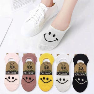 Colorful bamboo ankle socks with smiley face designs and casual white sneakers. Each sock features eco-friendly bamboo material branding from. Perfect for stylish and comfortable footwear options.
