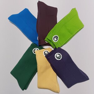 Six pairs of colorful cotton socks displayed in a x shape on a light gray background. Each pair features a small cotton tag with logo, emphasizing comfort and style. Perfect for casual and everyday wear.